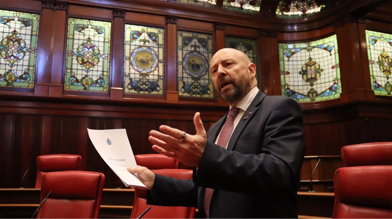 Brian Walker speaking in Parliament while holding a document